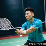 배드민턴과 웨이트 트레이닝 병행법 - A focused male badminton player in mid-action on an indoor court, wearing athletic shorts and a mois...